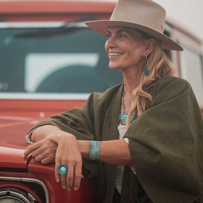 Woman wearing Frankie - Plymouth Satellite bracelet and ring sitting on a red vintage car smiling.