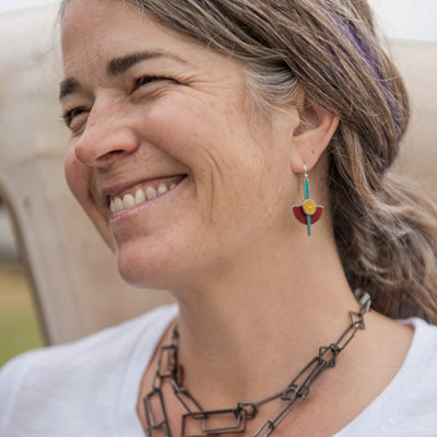 Irene - Ford & Chevy earrings worn by a smiling woman featuring original car paint and sterling silver wires